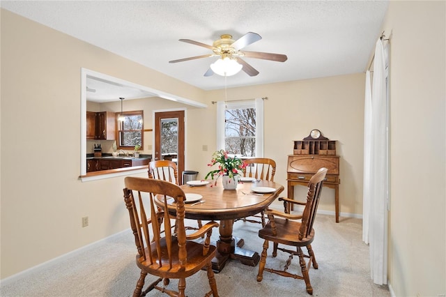 dining space featuring a textured ceiling, light colored carpet, and ceiling fan