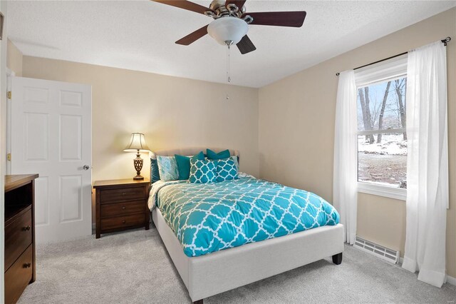 bedroom with ceiling fan, light colored carpet, a textured ceiling, and a baseboard heating unit