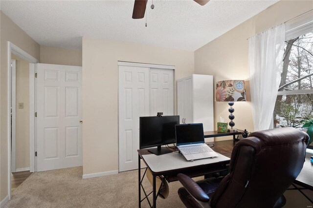 home office with light carpet, ceiling fan, and a textured ceiling