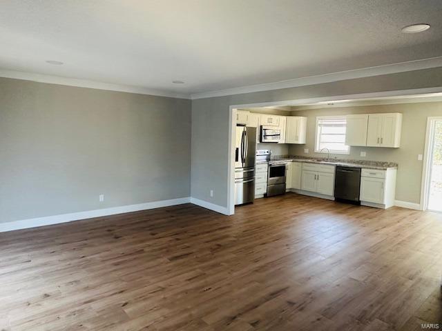 kitchen with sink, dark hardwood / wood-style floors, ornamental molding, white cabinetry, and stainless steel appliances