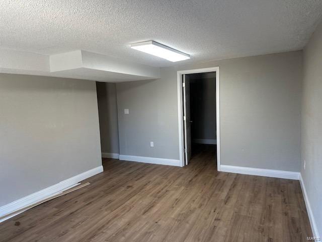 basement with hardwood / wood-style floors and a textured ceiling