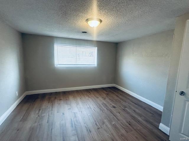 unfurnished room featuring dark hardwood / wood-style floors and a textured ceiling