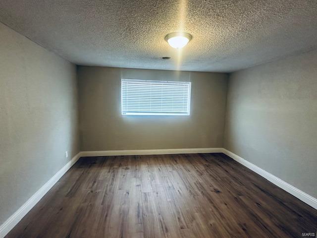 spare room featuring dark hardwood / wood-style floors and a textured ceiling