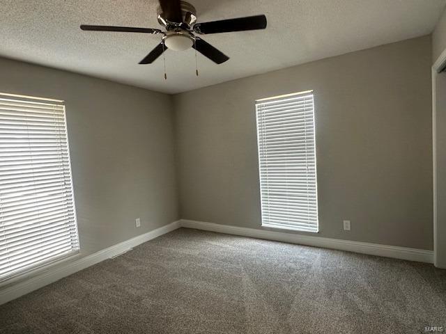 carpeted spare room with ceiling fan and a textured ceiling