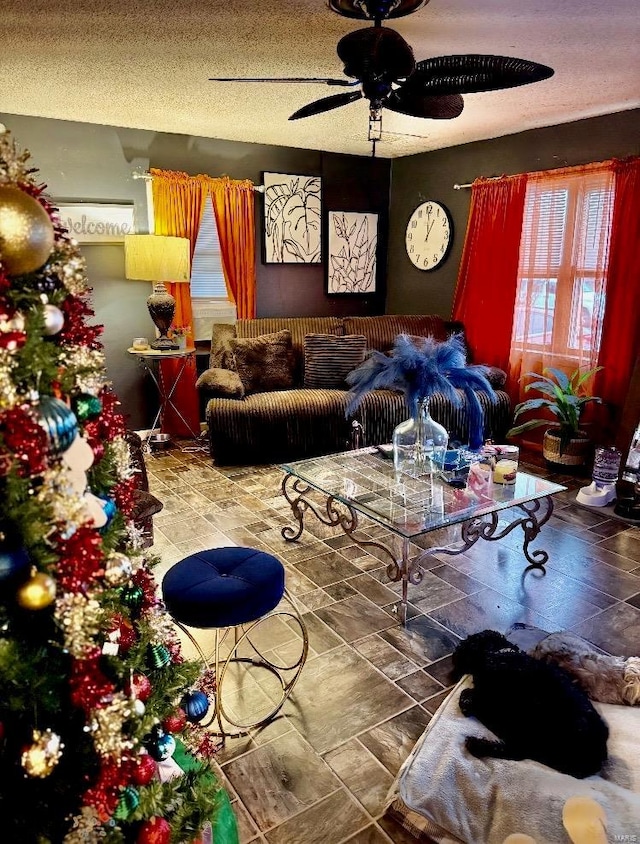 living room featuring ceiling fan and a textured ceiling