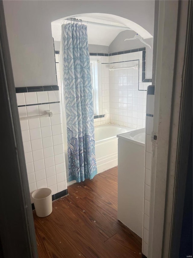 bathroom featuring tile walls, hardwood / wood-style floors, and shower / bath combination with curtain