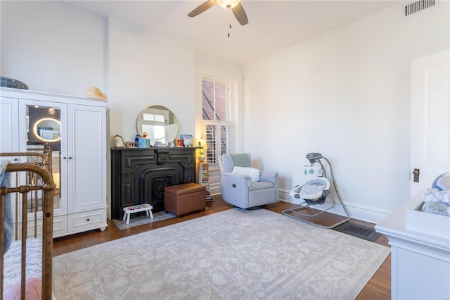 living area featuring ceiling fan, dark hardwood / wood-style flooring, and a wood stove