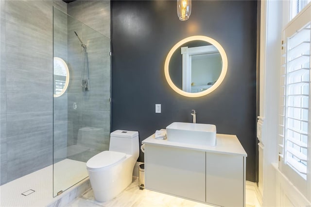 bathroom with a tile shower, vanity, toilet, and a healthy amount of sunlight