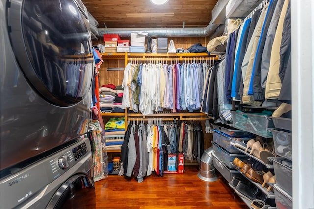 walk in closet featuring stacked washer and dryer and dark wood-type flooring