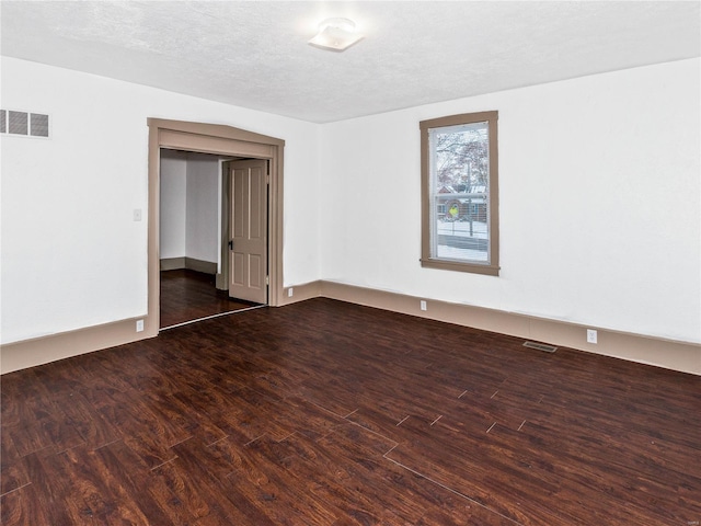 spare room with dark hardwood / wood-style floors and a textured ceiling