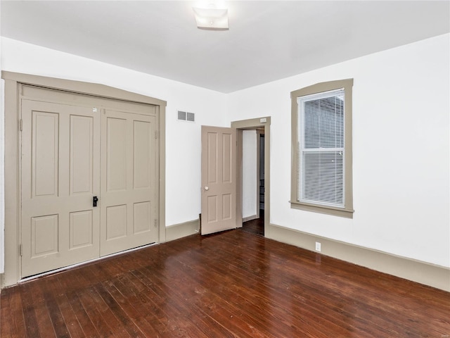 unfurnished bedroom featuring a closet and dark hardwood / wood-style floors