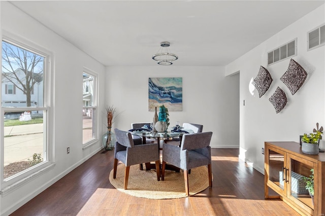 dining room with dark hardwood / wood-style floors, a healthy amount of sunlight, and a notable chandelier