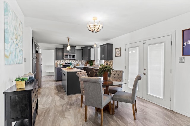 dining space featuring a chandelier, light wood-type flooring, and sink