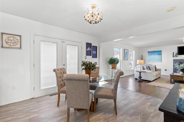 dining room featuring french doors, light wood-type flooring, and a notable chandelier