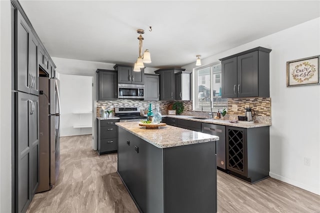 kitchen featuring stainless steel appliances, tasteful backsplash, light hardwood / wood-style flooring, decorative light fixtures, and a kitchen island