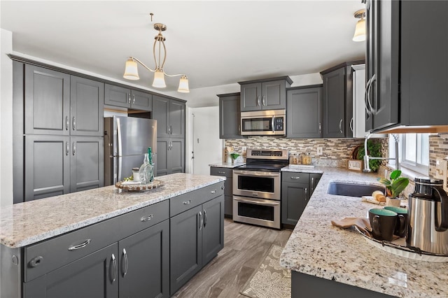 kitchen with pendant lighting, a center island, stainless steel appliances, and wood-type flooring