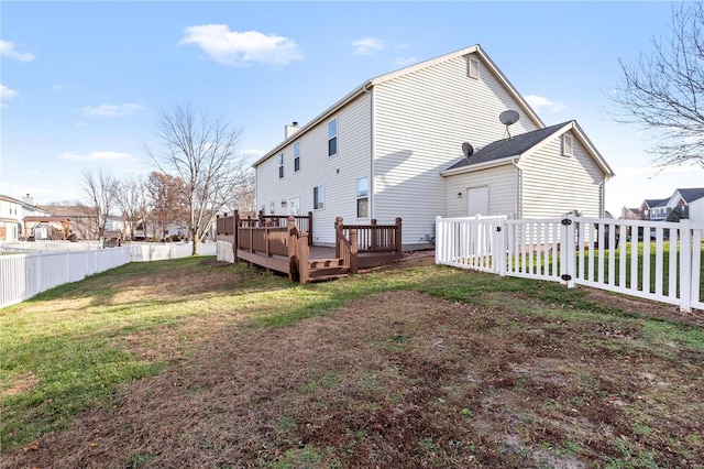 rear view of house with a lawn and a wooden deck