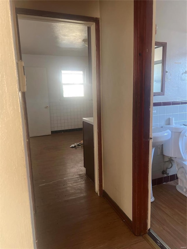 hall with dark hardwood / wood-style flooring and tile walls