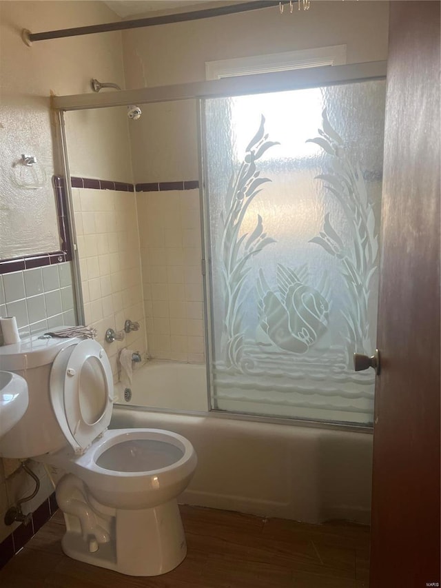 bathroom featuring shower / bath combination with glass door, hardwood / wood-style flooring, and toilet