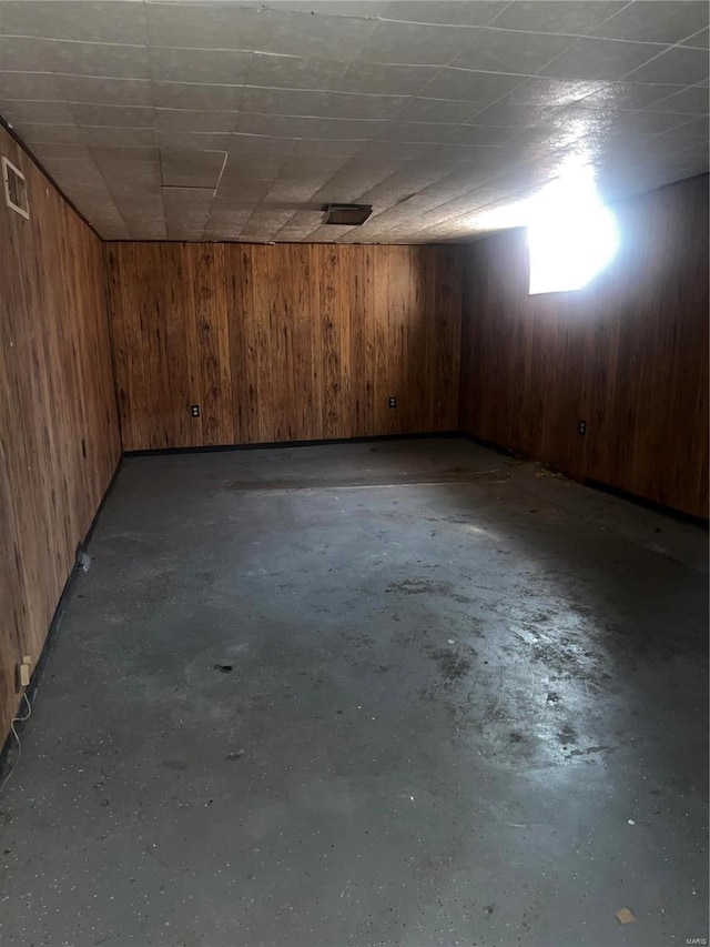 basement featuring a paneled ceiling and wooden walls