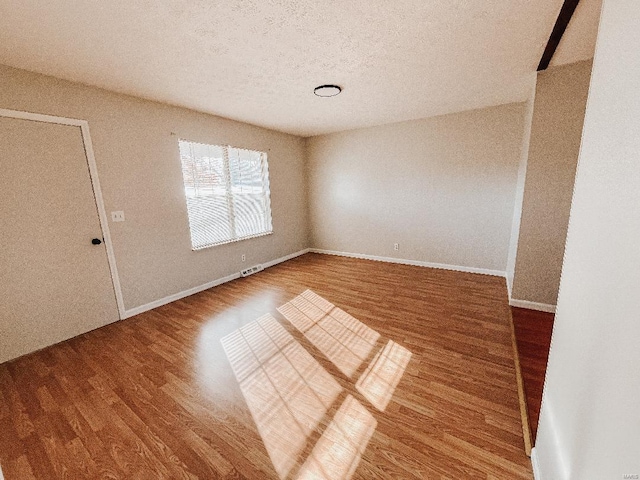 empty room featuring wood-type flooring and a textured ceiling