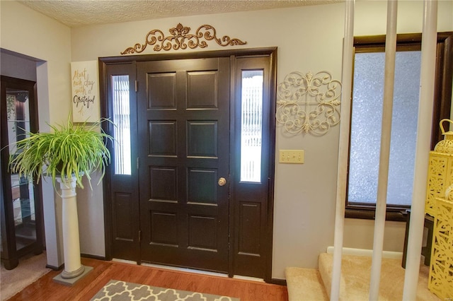 entryway with plenty of natural light, a textured ceiling, and hardwood / wood-style flooring