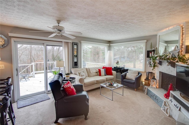 carpeted living room featuring a wealth of natural light, a fireplace, ceiling fan, and a textured ceiling