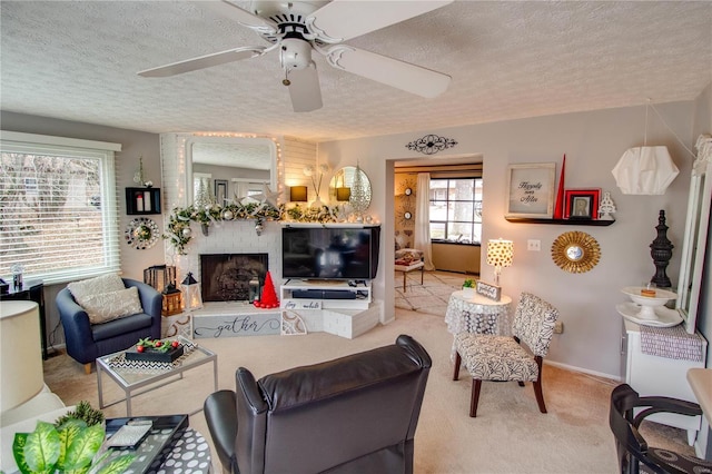 living room with ceiling fan, light colored carpet, a textured ceiling, and a brick fireplace