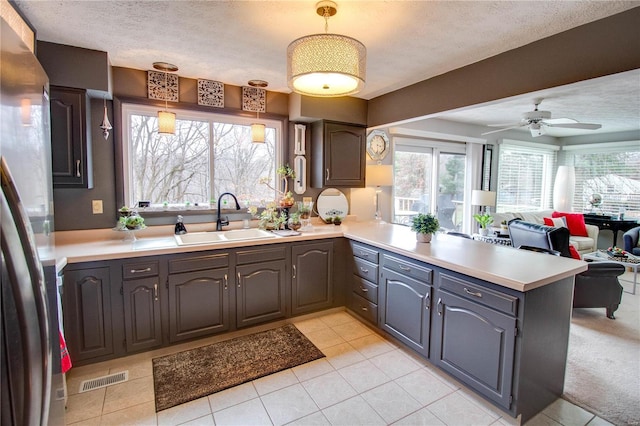 kitchen featuring sink, ceiling fan, stainless steel fridge, a textured ceiling, and kitchen peninsula