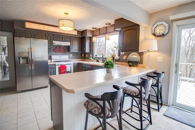 kitchen with a kitchen breakfast bar, white gas range, kitchen peninsula, and stainless steel refrigerator with ice dispenser