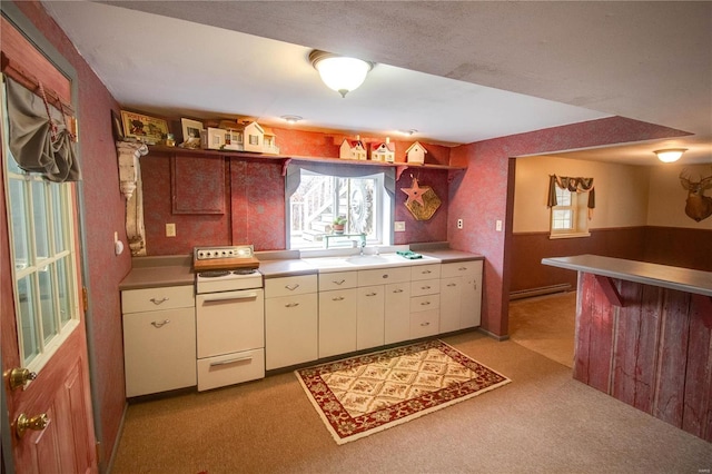 kitchen with light carpet, white range oven, a baseboard radiator, and plenty of natural light