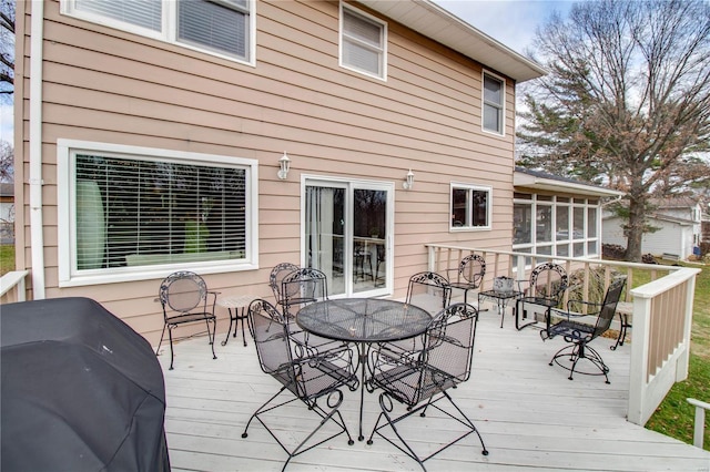 wooden deck featuring a sunroom and a grill