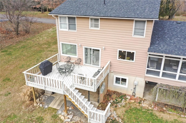 rear view of house with a sunroom, a yard, and a deck