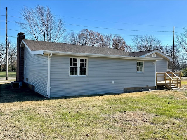 rear view of property with central AC unit and a yard