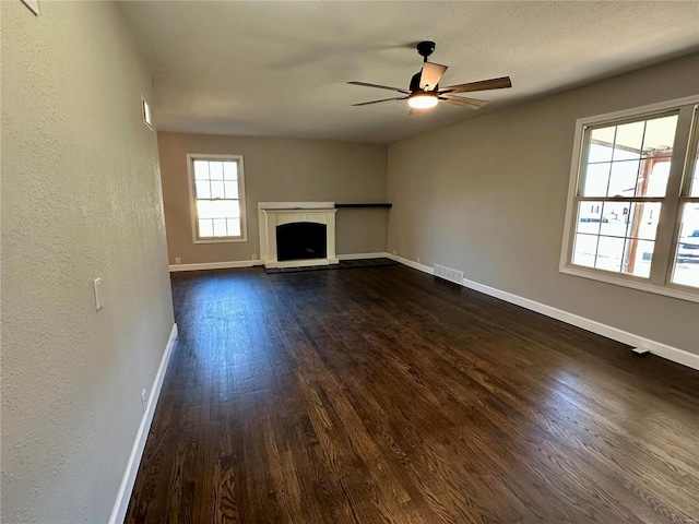 unfurnished living room featuring dark hardwood / wood-style flooring, a textured ceiling, and ceiling fan