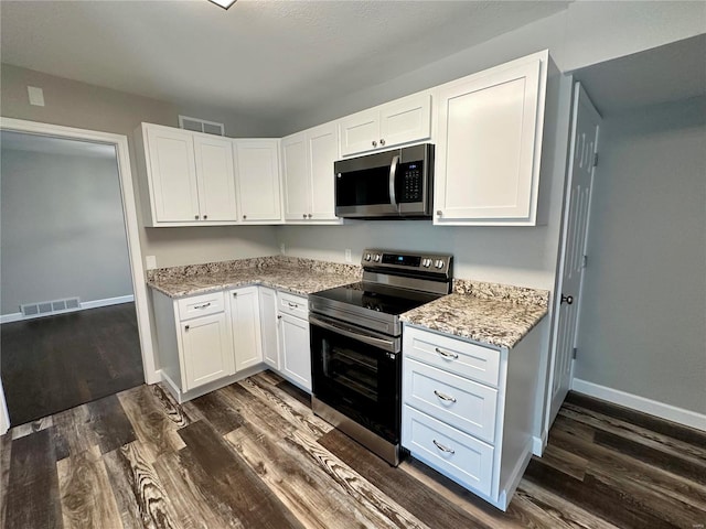 kitchen with dark hardwood / wood-style flooring, light stone countertops, stainless steel appliances, and white cabinets