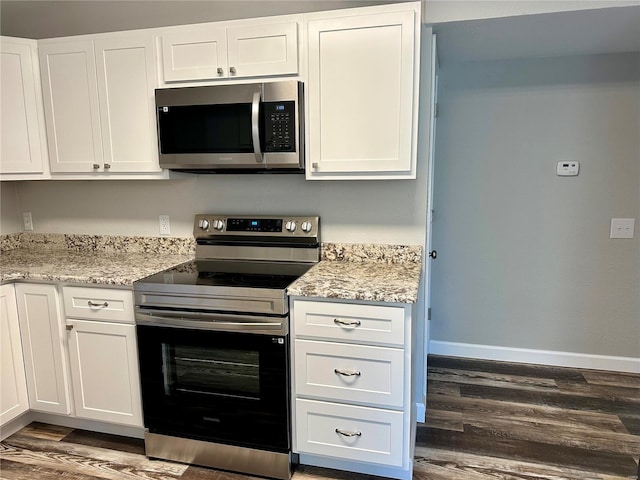 kitchen featuring white cabinetry, stainless steel appliances, light stone countertops, and dark wood-type flooring