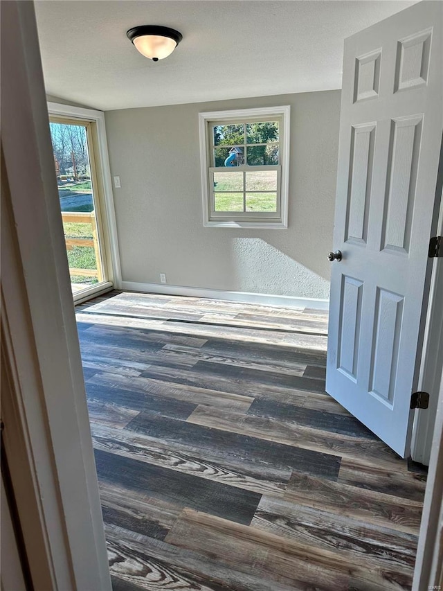 empty room featuring dark wood-type flooring and a healthy amount of sunlight