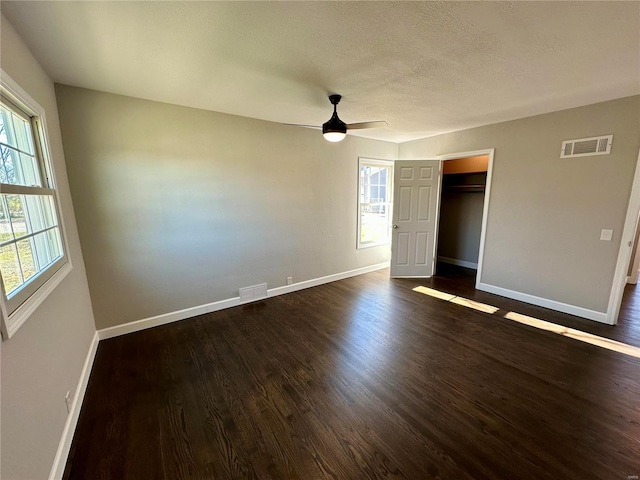 unfurnished bedroom featuring dark wood-type flooring, ceiling fan, a closet, and a textured ceiling