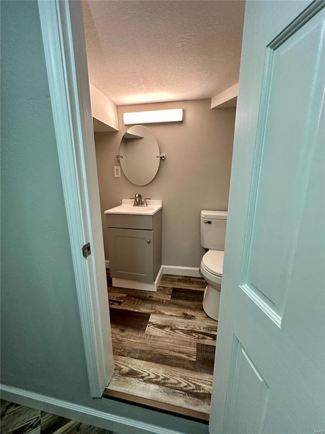 bathroom featuring hardwood / wood-style flooring, vanity, toilet, and a textured ceiling