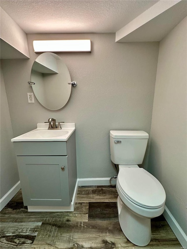 bathroom featuring vanity, hardwood / wood-style floors, a textured ceiling, and toilet