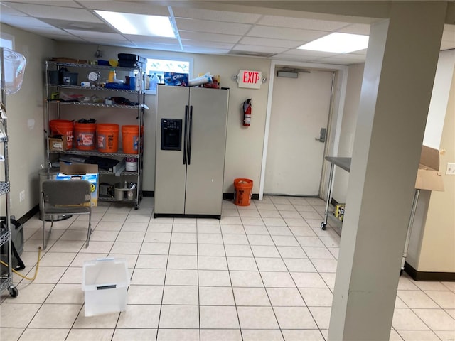 kitchen with stainless steel fridge with ice dispenser, light tile patterned floors, and a drop ceiling