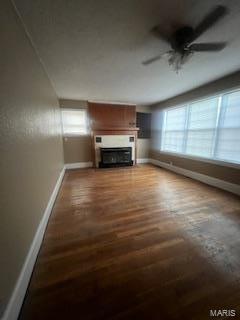 unfurnished living room with ceiling fan and dark hardwood / wood-style flooring