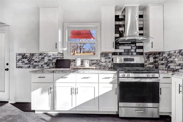 kitchen with light stone counters, white cabinets, wall chimney range hood, and stainless steel gas range