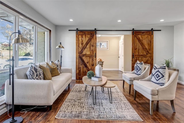 living room with a barn door and dark wood-type flooring