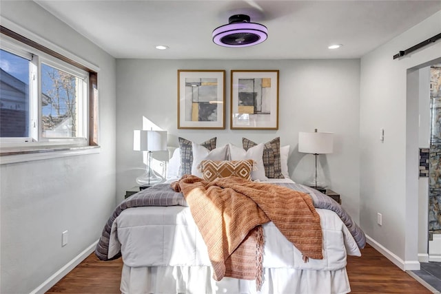 bedroom featuring a barn door and dark hardwood / wood-style floors