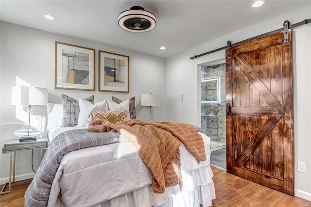 bedroom with a barn door and light hardwood / wood-style flooring