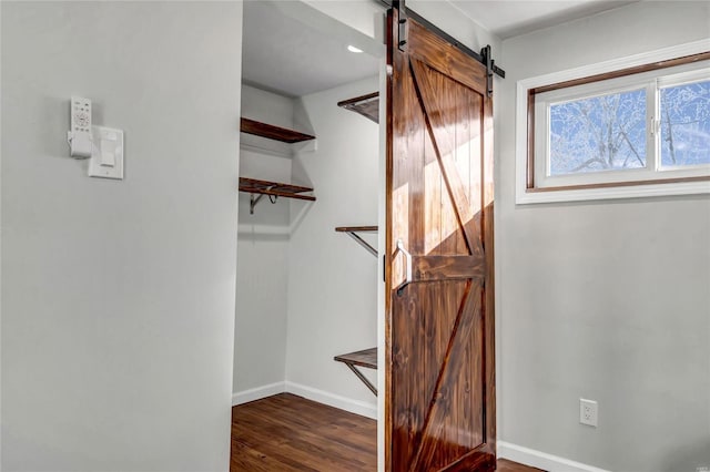 walk in closet with a barn door and dark hardwood / wood-style flooring