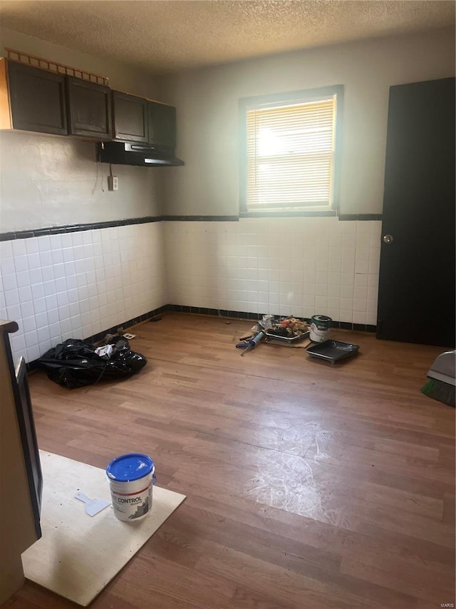 unfurnished dining area with a textured ceiling, tile walls, and hardwood / wood-style flooring