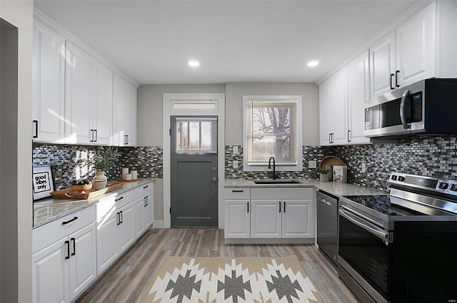 kitchen featuring sink, white cabinets, stainless steel appliances, and light hardwood / wood-style flooring